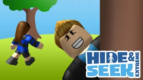 A wide, low-angle shot of two Roblox avatars playing Hide and Seek Extreme. A male avatar with a wide, mischievous smile is peeking out from behind a large brown tree trunk, while a female avatar with long brown hair, wearing a blue shirt and black pants, walks away from him. The background is a simple, stylized outdoor scene with a green grassy field and a single large tree. The playful and competitive nature of the image makes it a perfect visual for a blog post on Roblox games for couples.