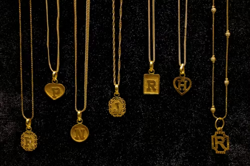 Elegant gold initial pendant necklaces on a black background, a perfect personalized jewelry gift idea for women for birthdays, anniversaries, and special occasions.