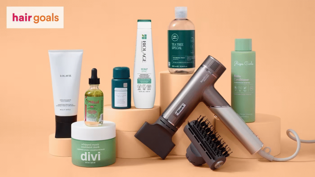 A flat lay display of various haircare products for women, including a bottle of shampoo, hair oil, a scalp serum, a moisturizing cream, and a compact hair dryer with an attachment. This luxury beauty gift set is a perfect self-care gift idea for women in 2025.