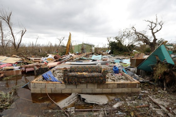 Devastating aftermath of Hurricane Melissa showing destroyed homes, debris, and floodwater in a residential area.