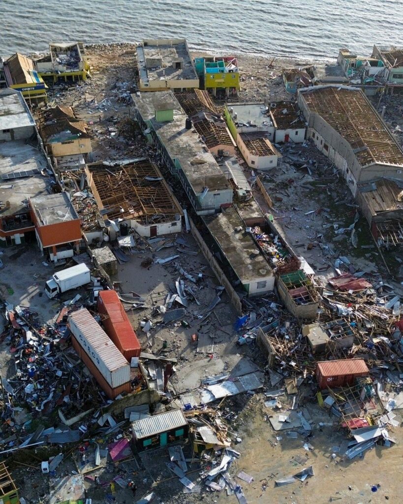 Aerial view of severe coastal town damage after Hurricane Melissa, showing widespread destruction, debris, and flooding across residential and commercial buildings. Black River Jamaica