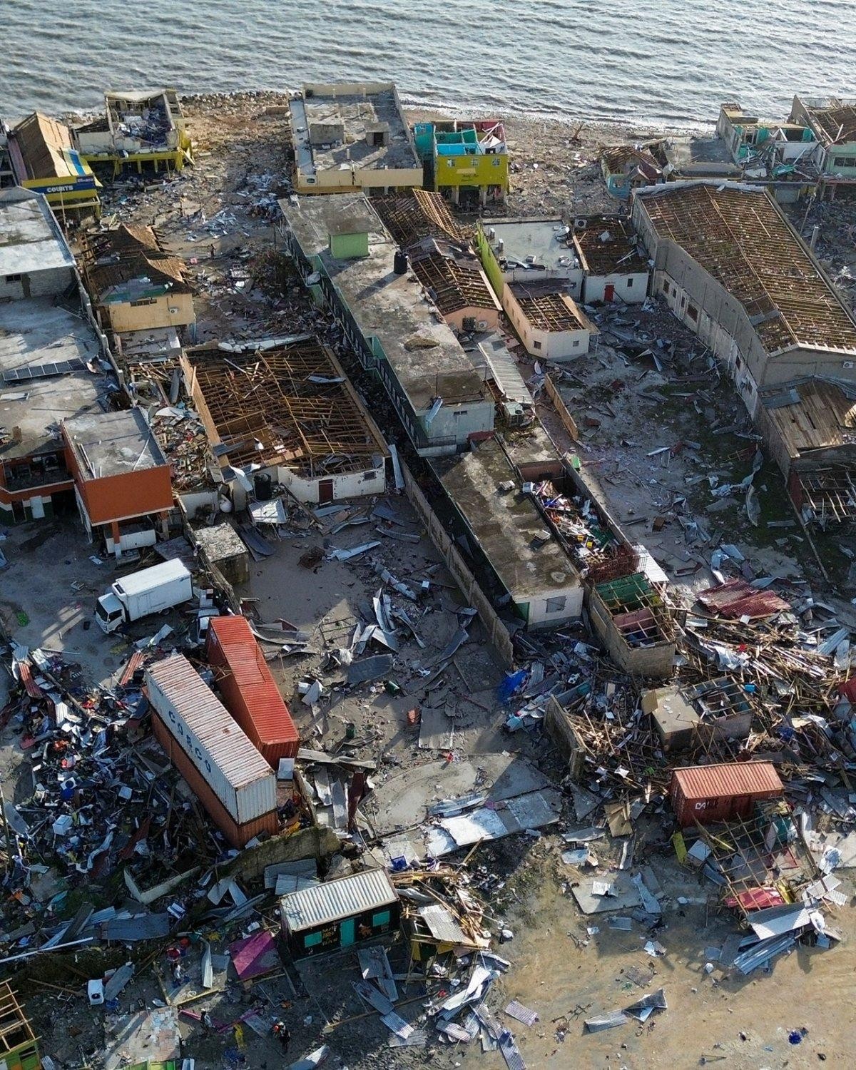 Aerial view of severe coastal town damage after Hurricane Melissa, showing widespread destruction, debris, and flooding across residential and commercial buildings. Black River Jamaica